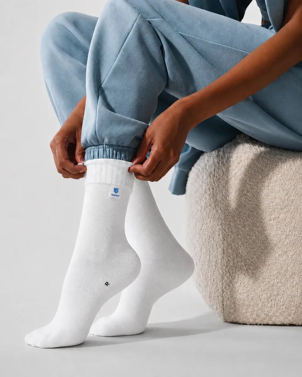 Pulling on a pair of white HydroSox while seated